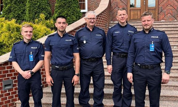 pięciu umundurowanych policjantów pozuje do zdjęcia na schodach