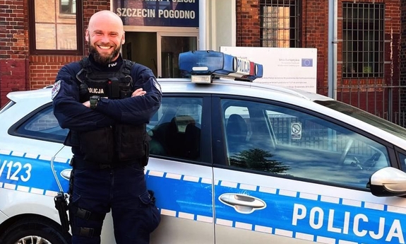 policjant stoi przy radiowozie policyjnym