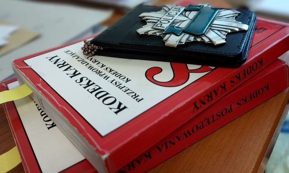 na stole leżą kodeksy karne na kodeksach leży policyjna metalowa gwiazda w etui