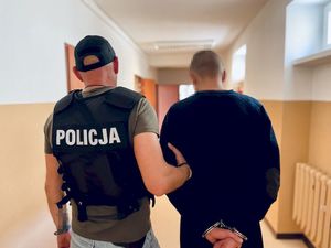 policjant z zatrzymanym zakutym w kajdanki