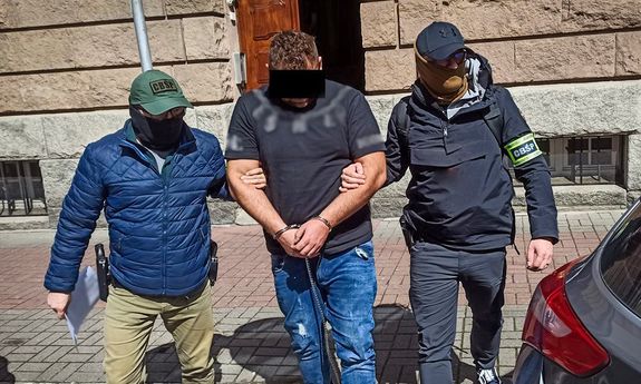 policjanci CBŚP prowadzą zatrzymanego do nieoznakowanego radiowozu
