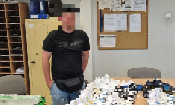 zabezpieczone przedmioty na stole, obok stoi policjant