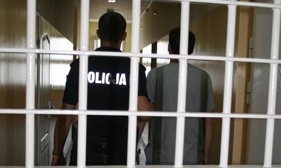 policjant z mężczyzną stoją za kratkami