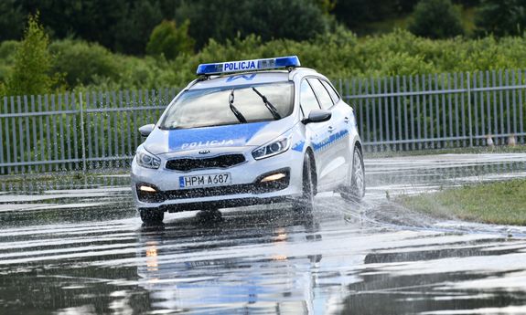radiowóz jedzie po mokrym torze