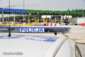 dach radiowozu z napisem Policja, w tle przejście graniczne