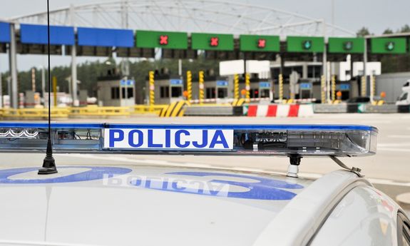 dach radiowozu z napisem Policja, w tle przejście graniczne
