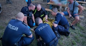 policjanci pochylają się nad kobietą i udzielają jej pomocy