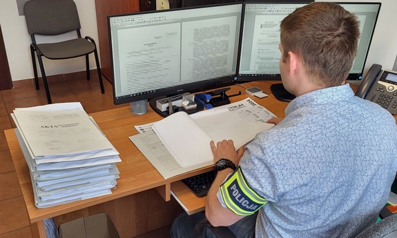nieumundurowany funkcjonariusz siedzi przy biurku, pisze na klawiaturze komputera