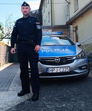 policjant stoi przed radiowozem policyjnym