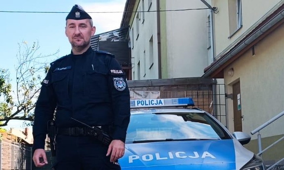 policjant stoi przed radiowozem policyjnym