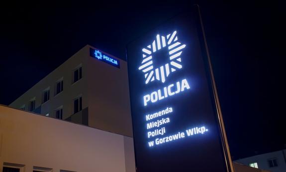 Pora nocna. Pylon informacyjny z napisem Komenda Miejska Policji w Gorzowie Wlkp., w tle budynek komendy