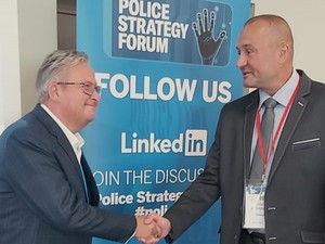 dwóch mężczyzn podających sobie dłonie na tle banera &quot;Strategicznego Forum Policyjnego&quot;