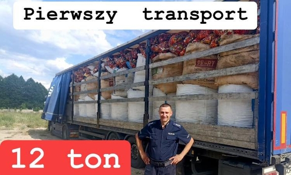 Policjant stoi na tle naczepy, na której stoją białe worki wypełnione nakrętkami. U góry napis: Pierwszy transport. W lewym dolnym rogu biały napis na czerwonym tle: 12 ton.