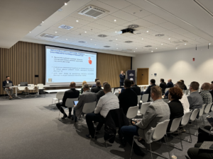 uczestnicy konferencji siedzą na sali słuchając prelegenta
