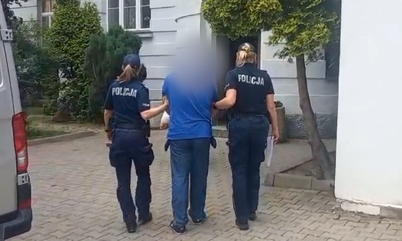 dwie umundurowane policjantki prowadzą zatrzymanego mężczyznę