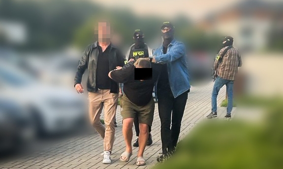 funkcjonariusze prowadza zatrzymanego