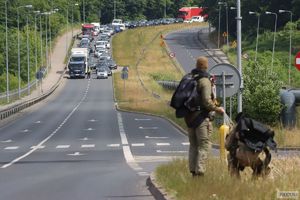 dwóch spadochroniarzy stoi tyłem do aparatu i patrzą przed siebie na ruch zablokowany przez policjantów