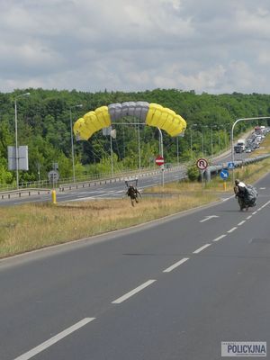 spadochroniarz ląduje na moście, obok drugi na niego patrzy