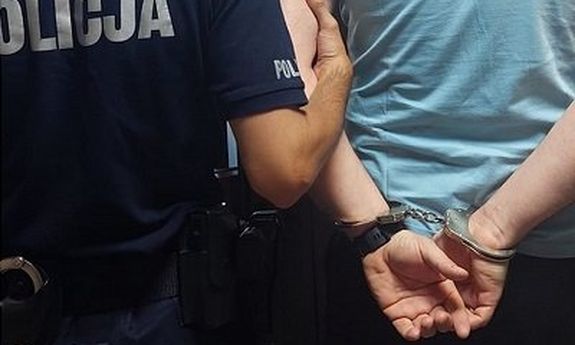 policjant z zatrzymanym mężczyzną skutym w kajdanki