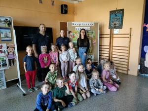 Para policjantów pozuje do zdjęcia z grupą dzieci i ich opiekunem.