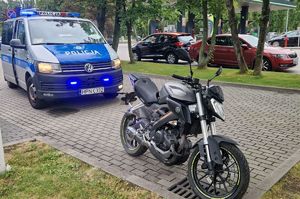 radiowóz z włączonymi światłami w kolorze niebieskim i czarny motocykl