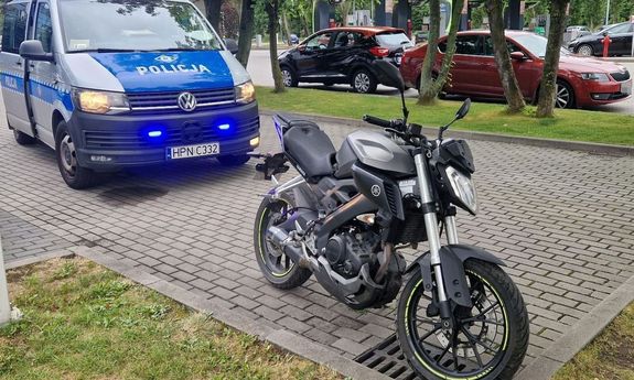 radiowóz z włączonymi światłami w kolorze niebieskim i czarny motocykl