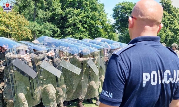 policjant stoi naprzeciwko grupy żołnierzy