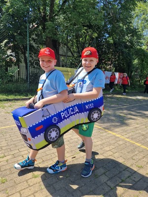 chłopcy idą ubrani w pluszowy radiowóz