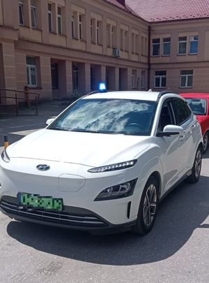 Nieoznakowany radiowóz z włączonym sygnałem świetlnym pod budynkiem