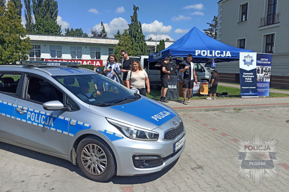 radiowóz policyjny na tle stoiska profilaktycznego