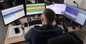 policjant siedzi przy biurku, stoi tam dużo ekranów z różnymi informacjami