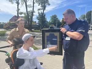chłopiec na wózku otrzymuje od policjanta upominek