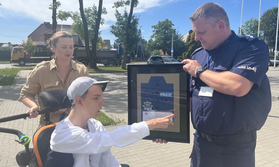 chłopiec na wózku otrzymuje od policjanta upominek