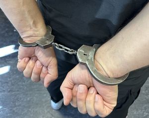 Ręce mężczyzny trzymane z tyłu  z założonymi kajdankami