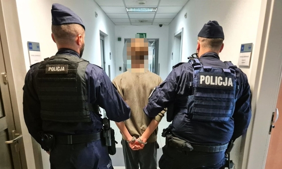policjanci prowadzą zatrzymanego korytarzem budynku komendy