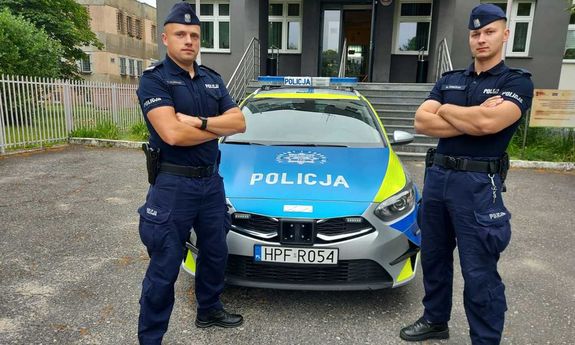 policjanci stoją na tle radiowozu