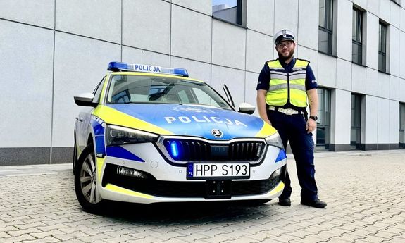 policjant stoi przy radiowozie