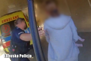 kadr z nagrania. Policjant prowadzi kobietę z dzieckiem do szpitala