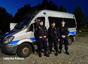 trzech policjantów stoi przed radiowozem