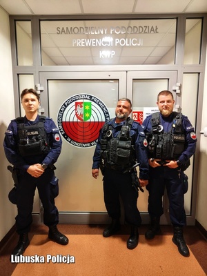 trzech policjantów stoi przed wejściem do budynku policji