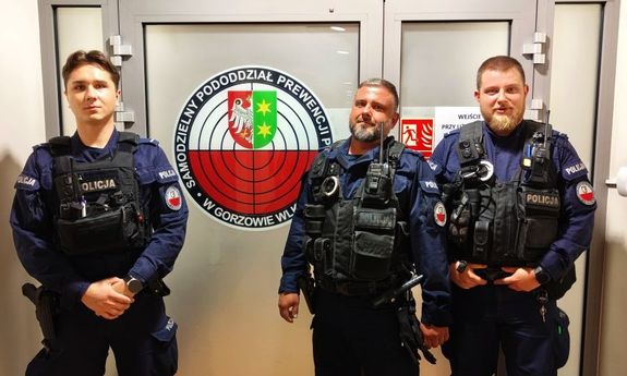 trzech policjantów stoi przed wejściem do budynku policji