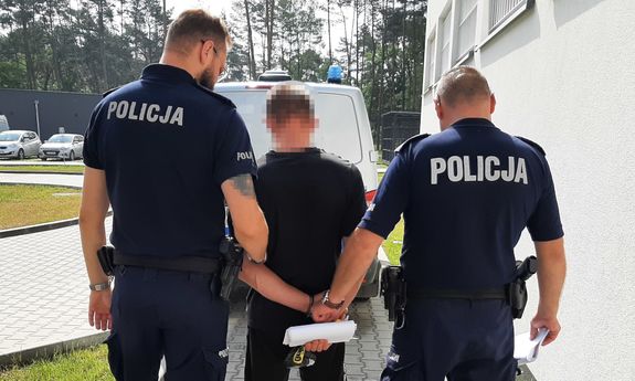 dwaj umundurowani policjanci prowadzą zatrzymanego - widok z tyłu
