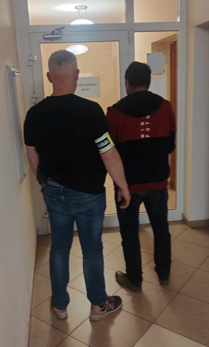 Policjant prowadzi zatrzymanego mężczyznę