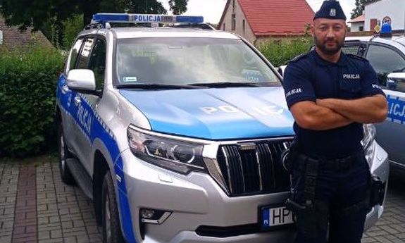 umundurowany policjant stoi przed radiowozem
