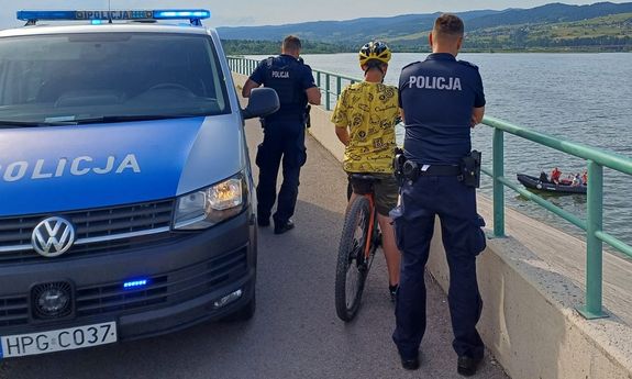 po lewej radiowóz, po prawej policjanci i odnaleziony chłopiec