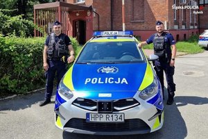 policjanci stoją przy radiowozie