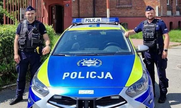 policjanci stoją przy radiowozie