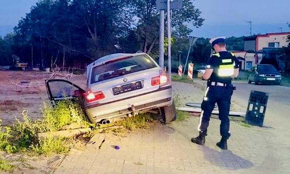 Policjant stoi przy samochodzie uciekiniera