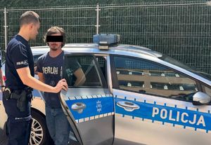 policjant stoi z zatrzymanym przy radiowozie