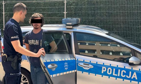 policjant stoi z zatrzymanym przy radiowozie